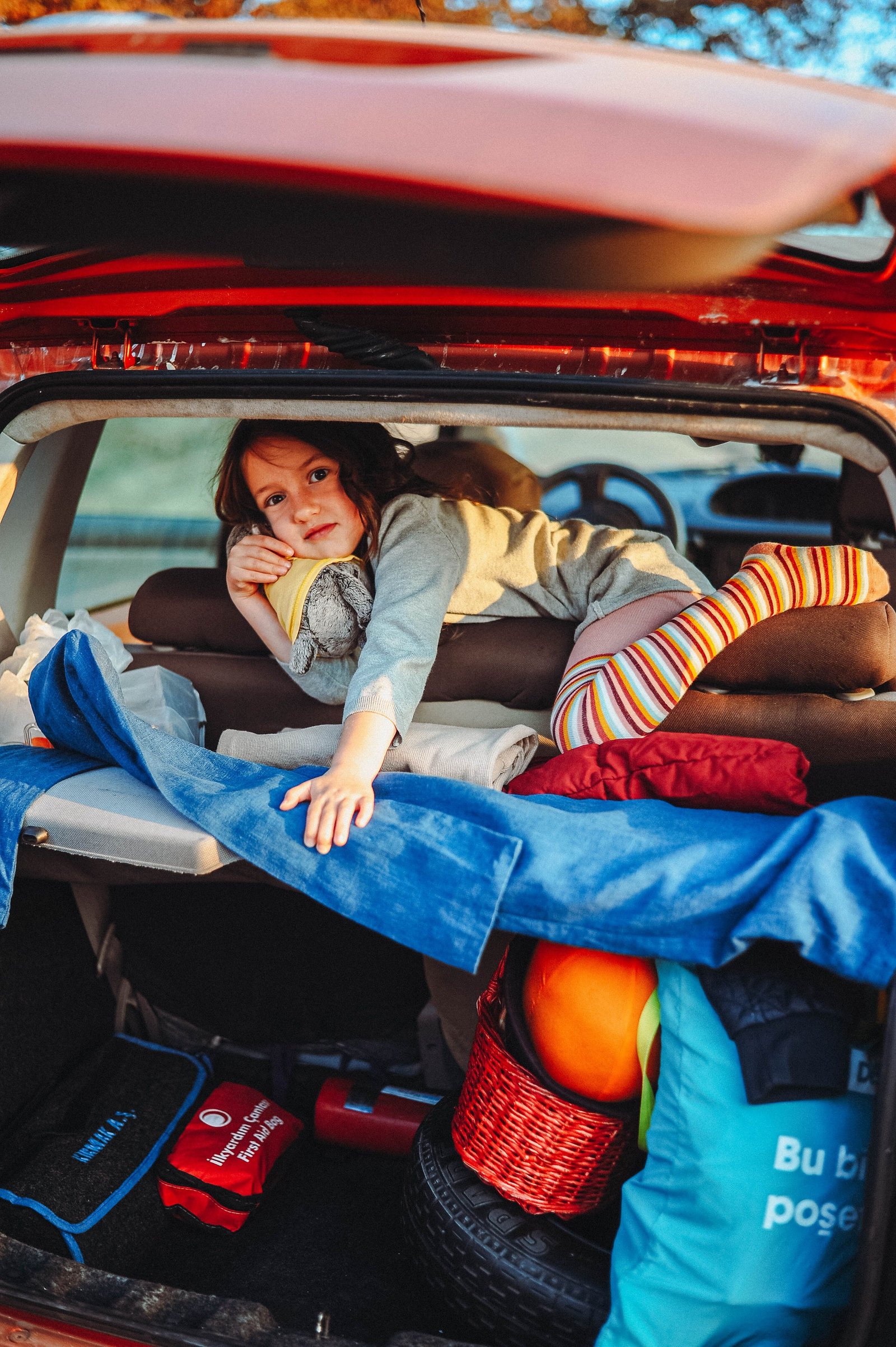 Enfant et bagages installés dans le coffre avant un départ en voiture