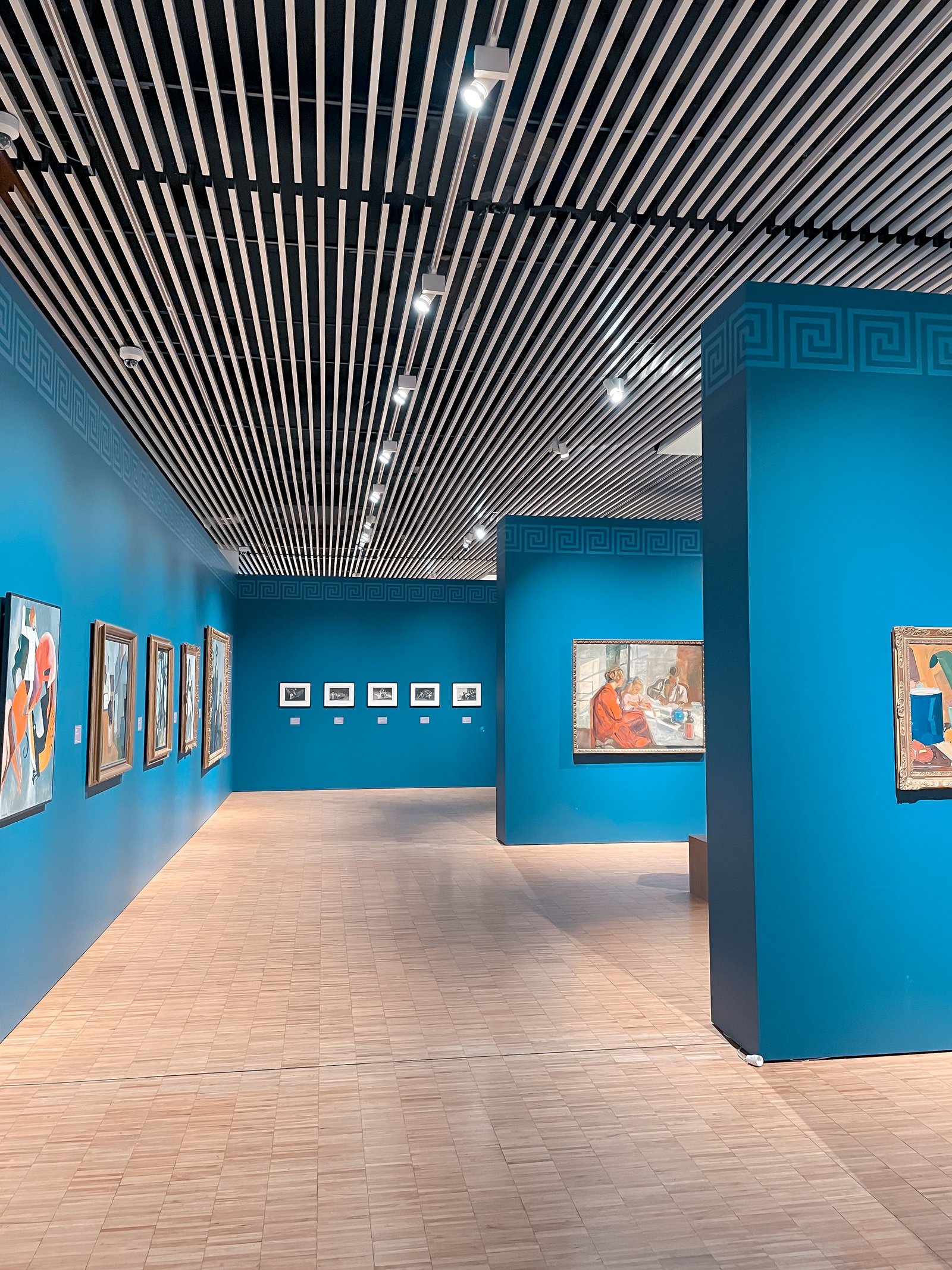Galerie de musée aux murs bleus présentant des peintures colorées